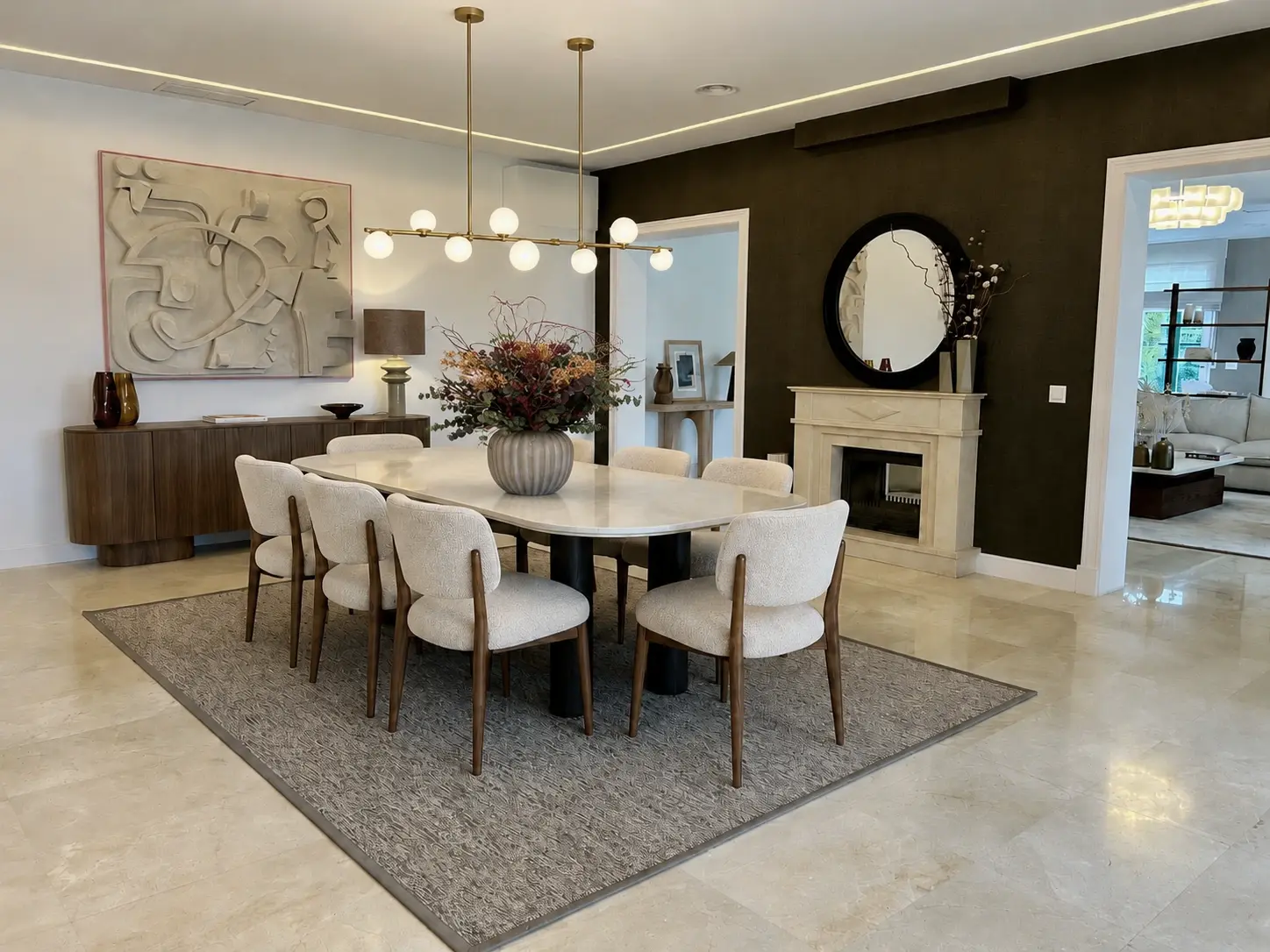 Comedor principal de La Moraleja con mesa ovalada, chimenea y arte escultórico